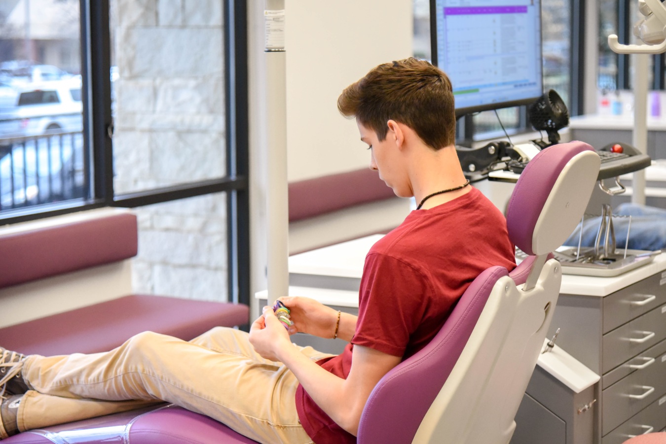 Teen patient holding colorful braces accessories at Marina Milstein Orthodontics in Auburn CA
